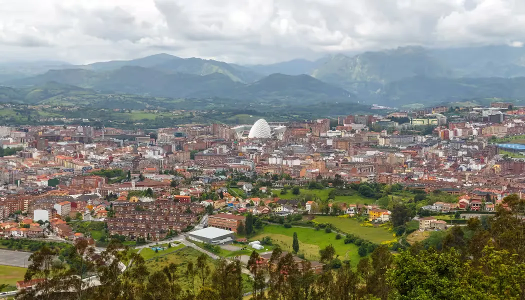 Una vista panorámica de Oviedo con verdes montañas al fondo.