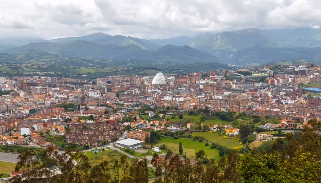 Una vista panorámica de Oviedo con verdes montañas al fondo.